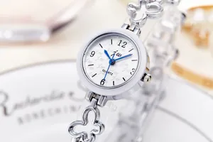 Detail shot of a silver butterfly-link bracelet watch with a white textured dial