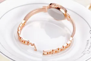 Détail du fermoir bijou en or rose et du bracelet à maillons d'une montre à quartz dame