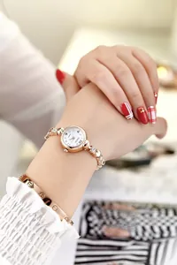 Close-up of rose gold quartz watch with rhinestone chain strap and small white dial