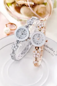 Dettaglio di orologi al quarzo floreali argento e oro rosa con sfondo di perle e profumo