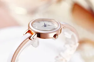 Détail du boîtier en or rose et bracelet céramique blanc avec aiguilles bleues du cadran