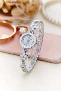 Dettaglio dell'orologio a bracciale argento con motivi floreali e strass su telefono rosa