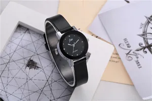 Detail of minimalist women's quartz watch with black dial and silver case on a white frame