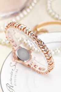 Close-up of rose gold leaf-shaped watch band with elegant pearl background display