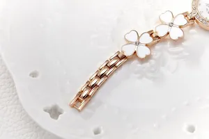 Macro view of rose gold watch band with clover charms and shimmering diamond accents