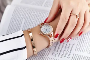 Close-up of rose gold watch with matching screw bracelet and nail ring on model