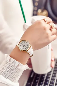 Close-up of white leather strap quartz watch with gold case on a female wrist
