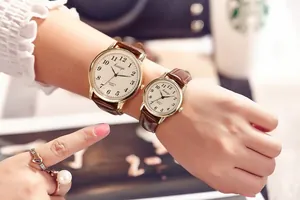 Close-up of couple wearing vintage quartz watches with brown leather straps and gold cases