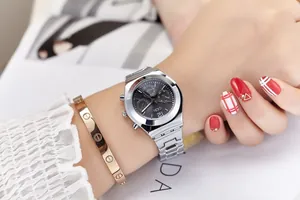 Macro shot of silver steel watch with dark grey dial paired with a gold screw bangle