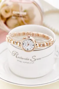 Close-up of rose gold quartz watch with rhinestone bracelet on white ceramic