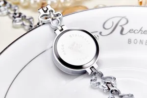 Macro shot of JW women's silver watch with stainless steel back and ornate chain strap