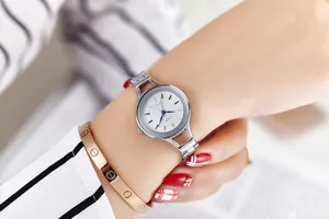 Close-up of GEDI silver watch with hollow chain band and blue hands on female wrist