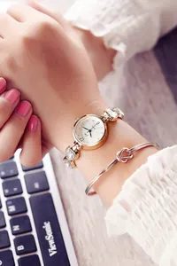 Detail einer roségoldenen Quarzuhr mit Zirkonia-Armband und passendem Knoten-Armreif