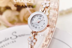 Dettaglio dell'orologio al quarzo floreale oro rosa con strass e cinturino bianco