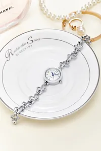 Close-up of women's silver butterfly chain watch with white dial on an elegant tray