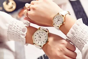 Macro shot of stylish gold quartz watches with white leather straps for couples