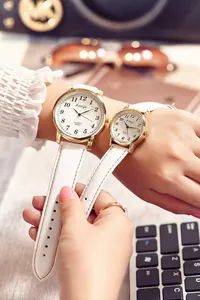 Close-up of couple watches with white leather straps and gold cases in a lifestyle setting