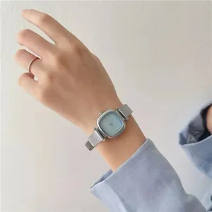 Détail du cadran carré bleu clair et bracelet en maille milanaise argentée au poignet