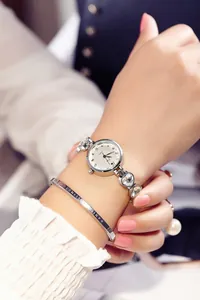 Nahaufnahme der silbernen Quarzuhr mit herzförmigem Kristallarmband am Handgelenk