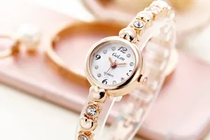 Detail of rose gold ladies' watch featuring heart-shaped links and rhinestone inlay