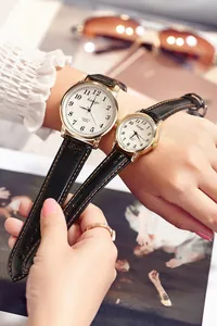 Close-up of casual quartz couple watches with black leather straps and gold cases