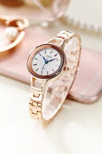 Detail of rose gold fashion watch featuring textured white dial and blue hands