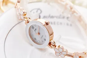 Dettaglio del cinturino in oro rosa con maglie a fiori bianchi e cristalli brillanti
