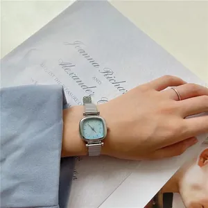Détail d'une montre à quartz pour femme avec cadran carré bleu clair et bracelet en maille argent
