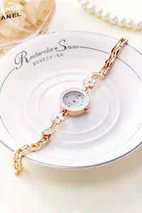 Dettaglio dell'orologio bracciale floreale oro rosa poggiato su un piatto in ceramica bianca