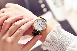Close-up of vintage quartz watch with black leather strap and gold case in a casual setting
