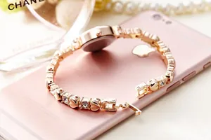 Close-up detail of rose gold ladies bracelet watch with heart links and crystals