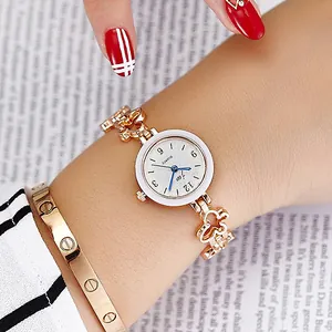 Elegant gold quartz watch with clover bracelet and screw design cuff on magazine background