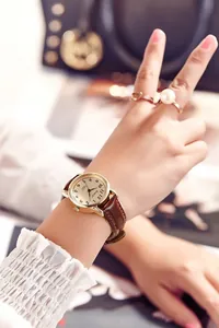 Elegant gold quartz watch for women featuring a brown leather strap and classic dial