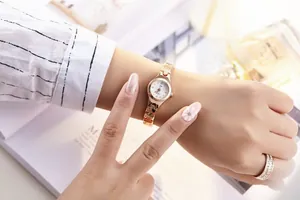 Close-up of rose gold small watch with white dial and sparkling diamond markers