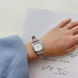 Gros plan détaillé d'une montre carrée argentée avec bracelet en maille au poignet