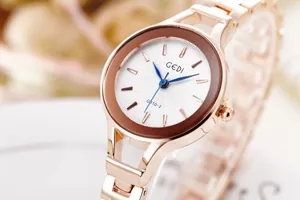Detailed close-up of rose gold watch dial with blue hands and rippled texture finish