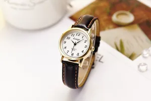 Detail of elegant ladies quartz watch with golden case and black stitched leather strap