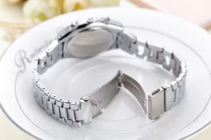 Detailed back view of silver steel watch with link strap and clasp in a porcelain dish