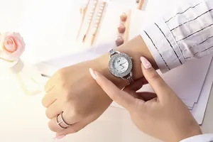 Close-up of a silver rhinestone-studded quartz watch with a white dial and silver metal strap