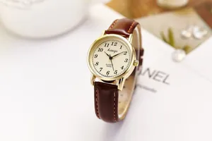 Detail of female quartz watch featuring gold alloy case and brown leather strap with stitching