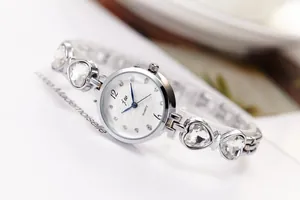 Makroaufnahme einer silbernen Modeuhr mit herzförmigem Diamantband und blauen Zeigern
