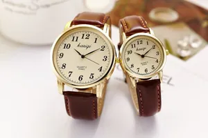 Close-up of golden couple quartz watches with beige dials and brown leather bands