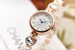 Details einer roségoldenen Quarzuhr mit Herz-Kristallarmband und hellblauen Zeigern