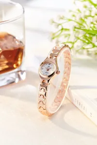 Detail of rose gold ladies quartz watch with rhinestone markers and H-link strap