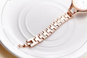 Detail of rose gold watch strap with unique H-link design on a white ceramic tray