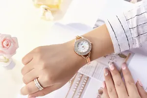 Detail of rose gold quartz watch with rhinestones worn next to pink roses