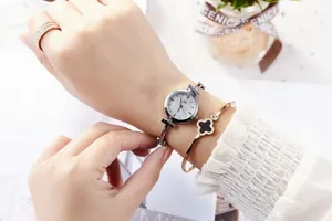 Close-up of a silver dial watch with a clover bracelet and pavé ring set for women