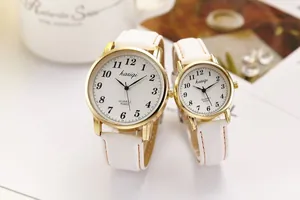 Detail of quartz couple watch set with white leather straps and golden cases on a table