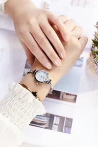 Close-up of women's silver fashion watch with starry sky dial and clover bracelet charm