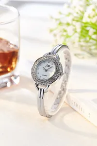 Macro detail of silver quartz watch with rhinestone bezel on a sleek metal chain bracelet